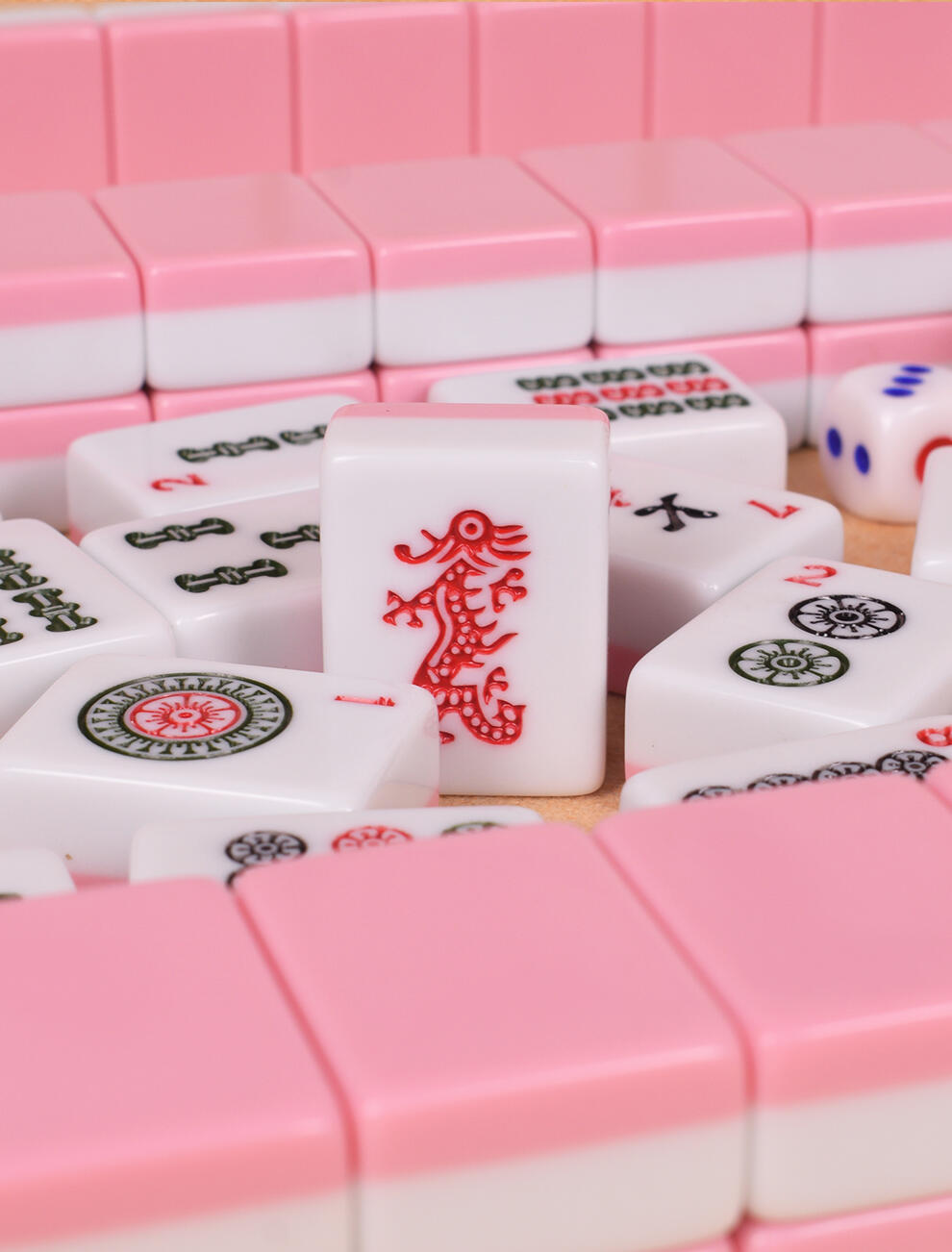 Pink mahjong tiles with red dragon design on a clean table